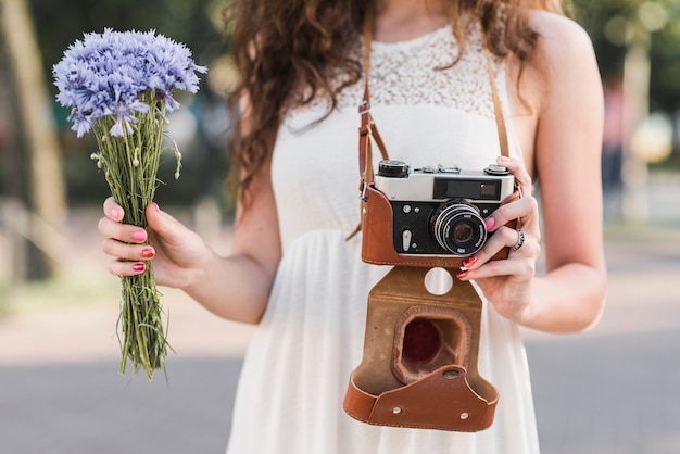 Macchina fotografica e fiori della holding della donna