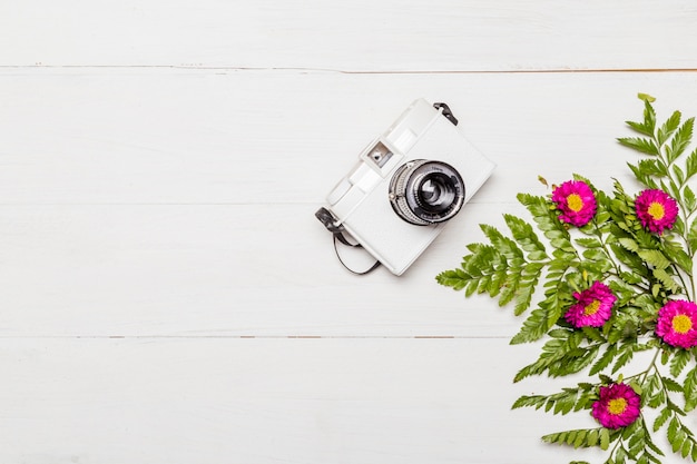 Macchina fotografica e fiori rosa con foglie verdi