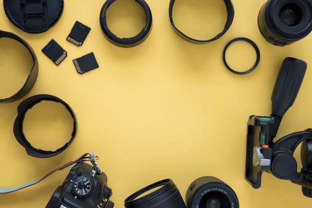 Macchina fotografica professionale moderna del dslr con gli accessori della macchina fotografica sopra fondo giallo