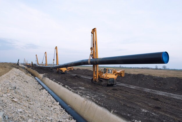 Macchine edili pesanti che trasportano e posizionano tubi del gas nel terreno