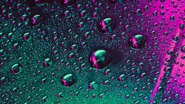 Macro di gocce di acqua verde e rosa sulla superficie