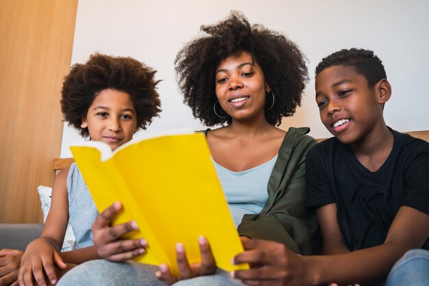 Madre afro che legge un libro ai suoi figli.