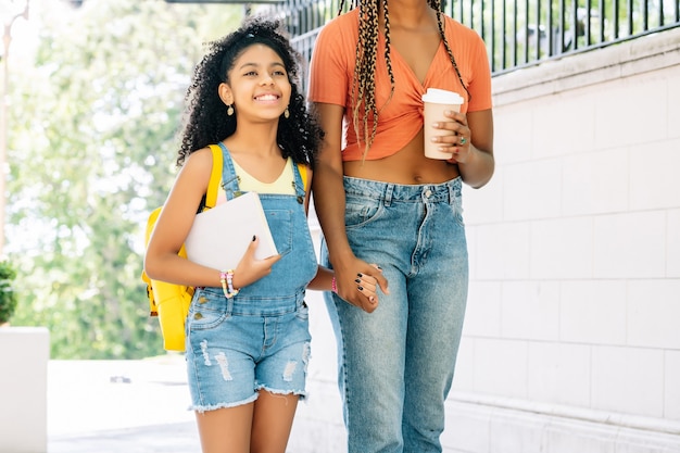 Madre afroamericana che porta sua figlia a scuola. Concetto di educazione.