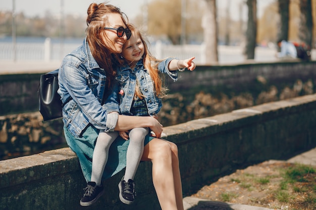 madre alla moda con i capelli lunghi e una giacca di jeans che giocano con la sua piccola e carina figlia