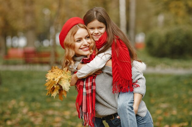 Madre alla moda con la figlia. Autunno giallo. Donna in una sciarpa rossa.