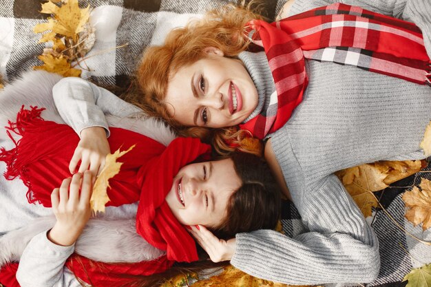 Madre alla moda con la figlia. Autunno giallo. Donna in una sciarpa rossa.