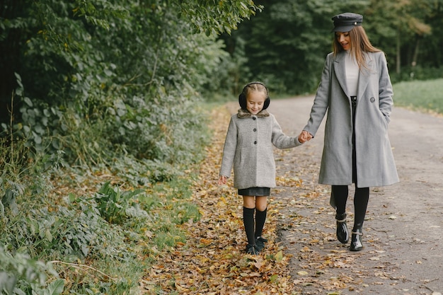 Madre alla moda con la figlia. La gente cammina fuori. Donna in un cappotto grigio.