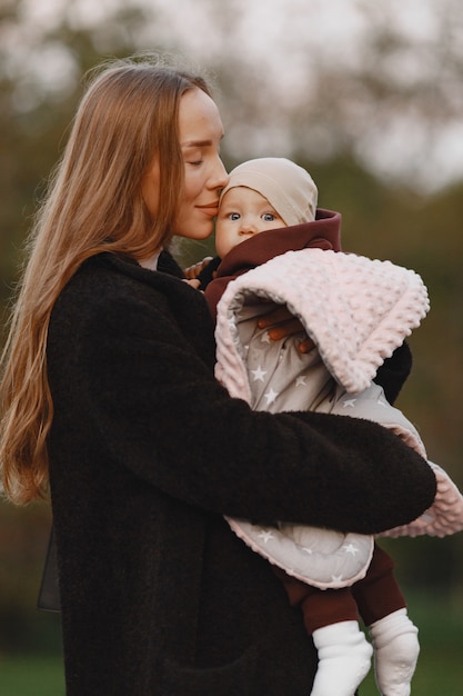 Madre alla moda con la figlia. La gente cammina fuori. Donna in una giacca nera.