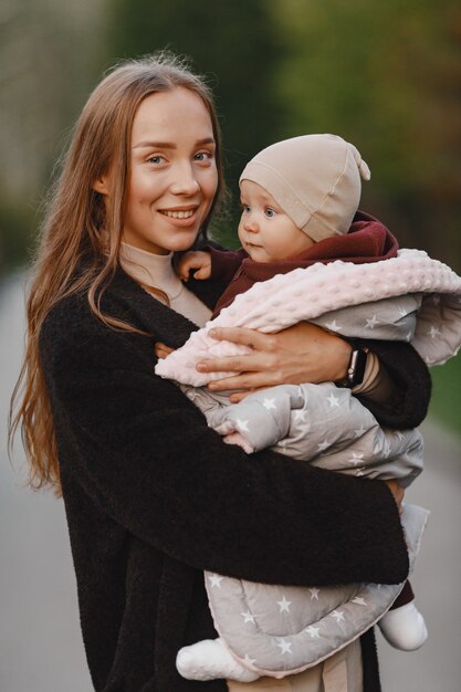 Madre alla moda con la figlia. La gente cammina fuori. Donna in una giacca nera.