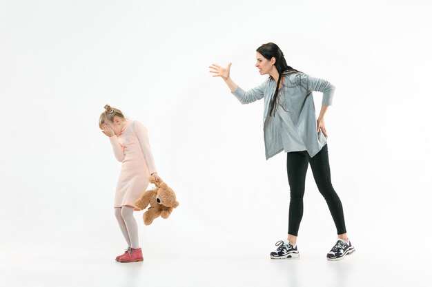 Madre arrabbiata che rimprovera sua figlia a casa. Studio shot di famiglia emotiva. Emozioni umane, infanzia, problemi, conflitti, vita domestica, concetto di relazione