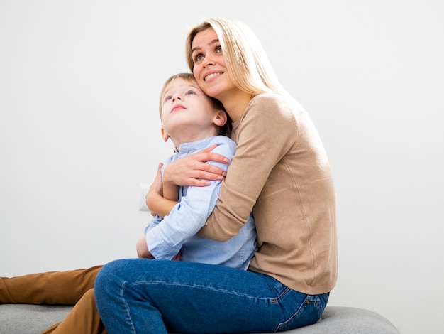 Madre bionda di vista frontale che abbraccia suo figlio