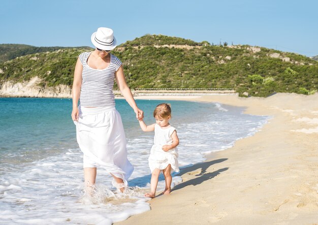 Madre caucasica che cammina sulla spiaggia con sua figlia durante il giorno