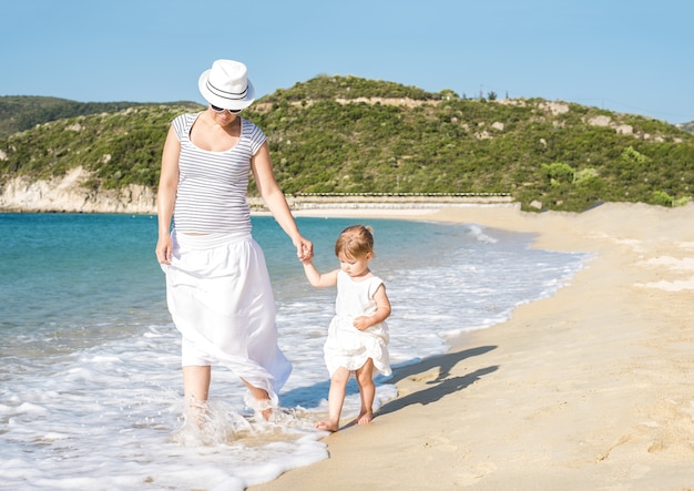 Madre caucasica che cammina sulla spiaggia con sua figlia durante il giorno