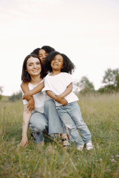 Madre caucasica e due sue figlie afroamericane che si abbracciano insieme all'aperto