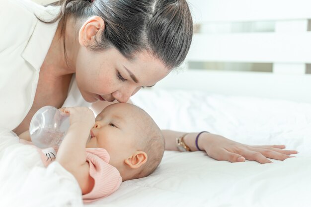 Madre che bacia un bambino che sta bevendo da una bottiglia