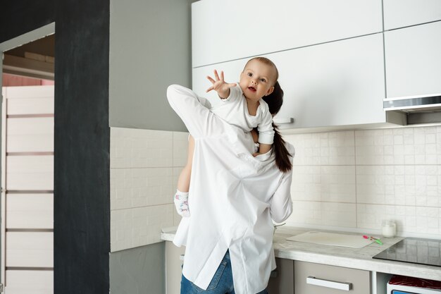 Madre che gioca con il bambino piccolo in cucina