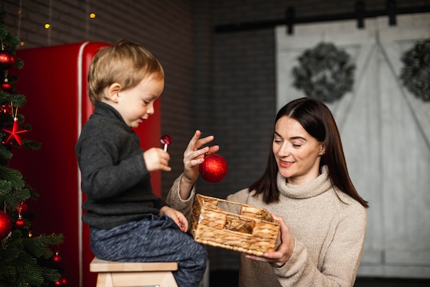 Madre che insegna al figlio come decorare l'albero di Natale