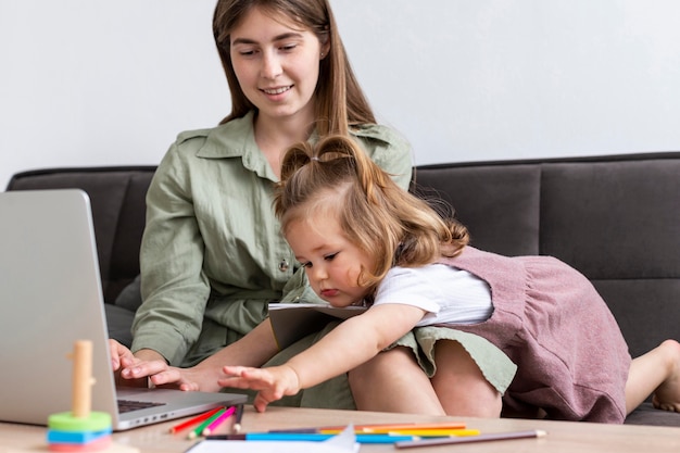 Madre che lavora al computer portatile con il bambino