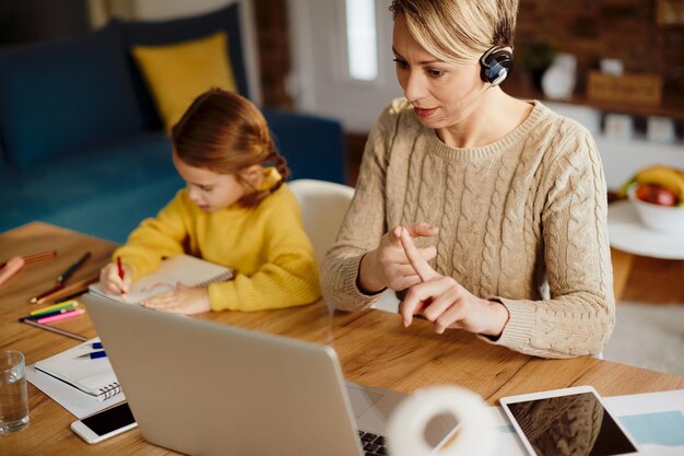 Madre che lavora con una chiamata in conferenza sul laptop a casa