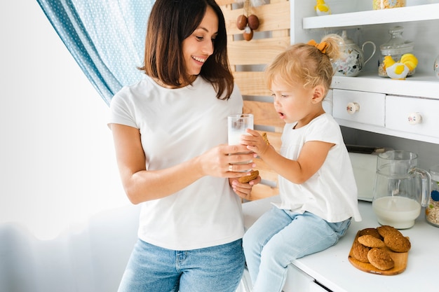 Madre che offre un bicchiere di latte a sua figlia