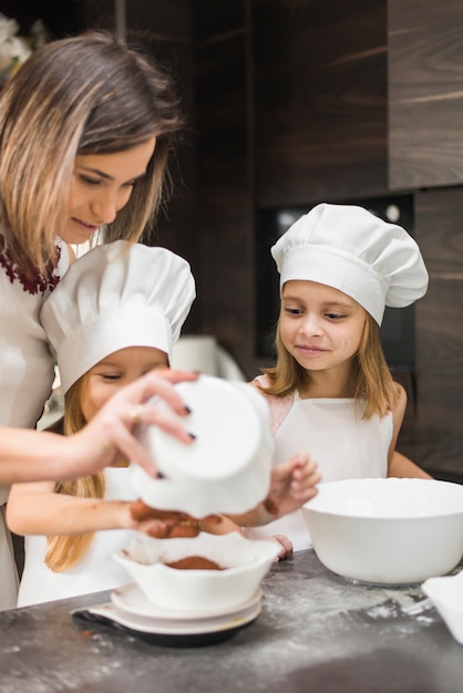 Madre che prepara il cibo in cucina con le sue due figlie