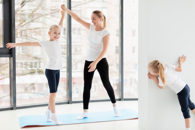 Madre che risolve con le figlie a casa sulla stuoia di yoga