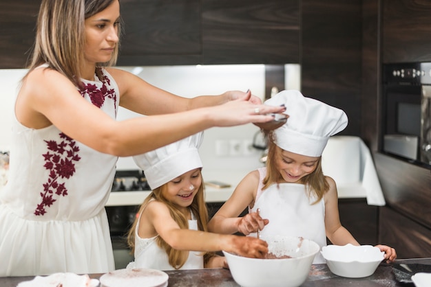 Madre che setaccia la polvere di cacao attraverso il colino mentre la figlia si mescola nella ciotola