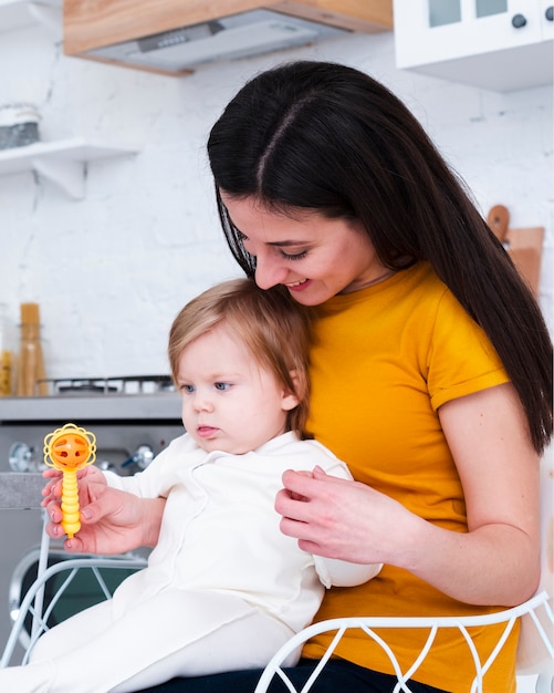 Madre che tiene bambino che gioca con il giocattolo