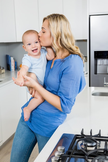 Madre che tiene il suo bambino ragazzo in cucina