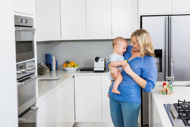 Madre che tiene il suo bambino ragazzo in cucina