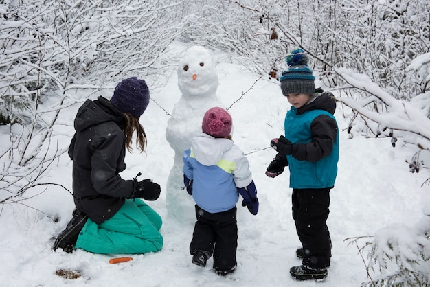 Madre con bambini che fanno pupazzo di neve