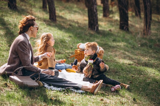 Madre con bambini che hanno picnic nella foresta