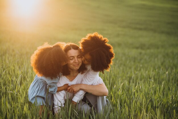 Madre con due bambini afroamericani al campo al tramonto