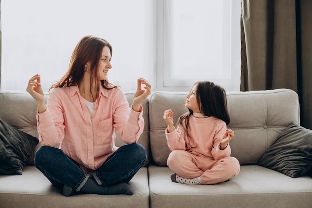 Madre con figlia che pratica yoga a casa sul divano