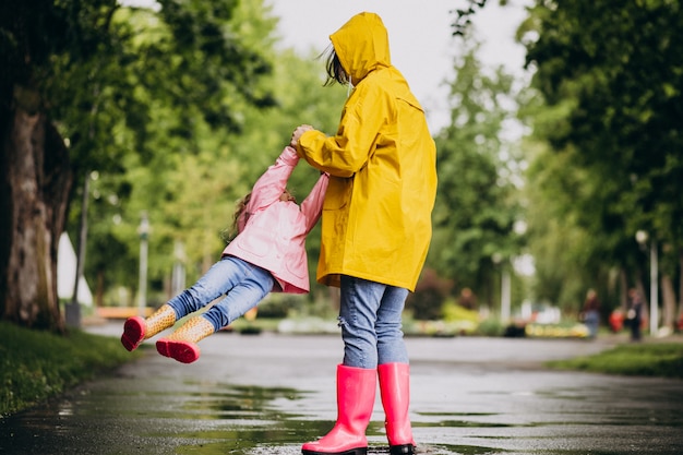 Madre con figlia divertirsi nel parco in un tempo piovoso