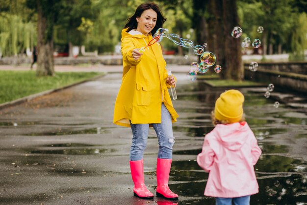 Madre con figlia divertirsi nel parco in un tempo piovoso