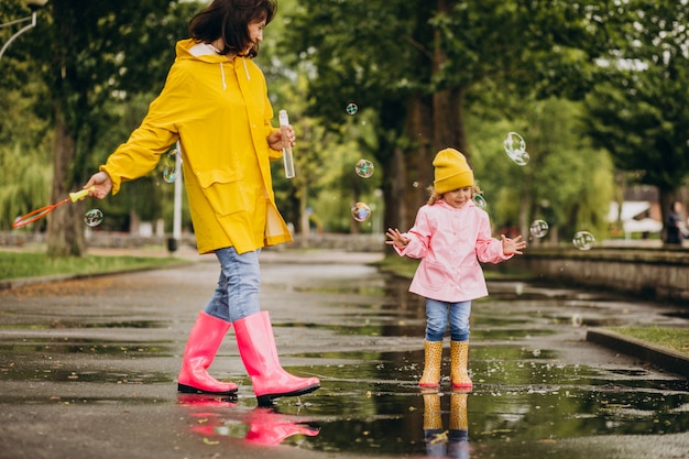 Madre con figlia divertirsi nel parco in un tempo piovoso