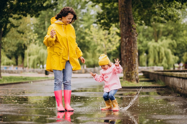 Madre con figlia divertirsi saltando nelle pozzanghere