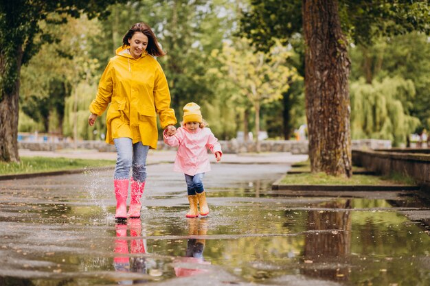 Madre con figlia divertirsi saltando nelle pozzanghere