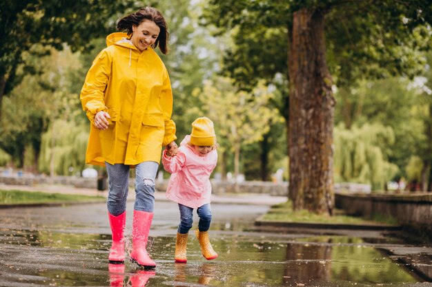 Madre con figlia divertirsi saltando nelle pozzanghere