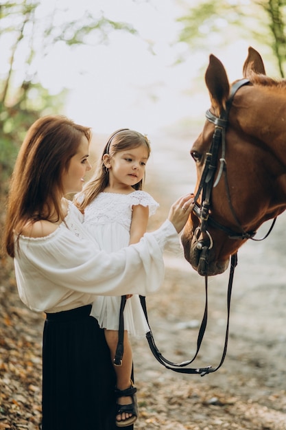 Madre con figlia e cavallo nella foresta