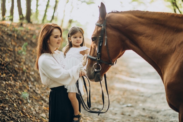 Madre con figlia e cavallo nella foresta