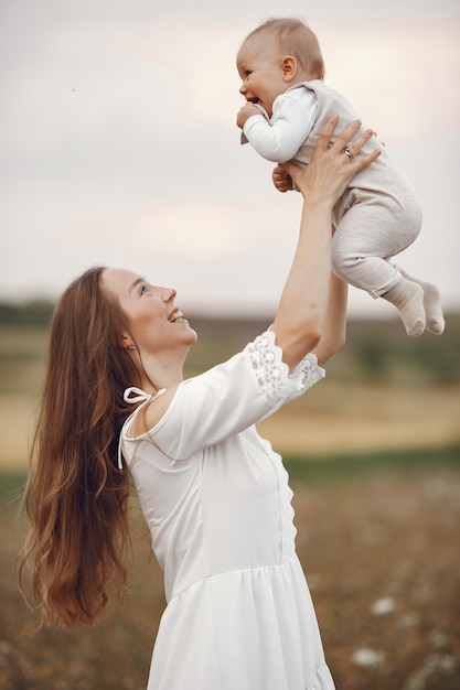 Madre con figlia. Famiglia in un campo. Ragazza appena nata. Donna in abito bianco.