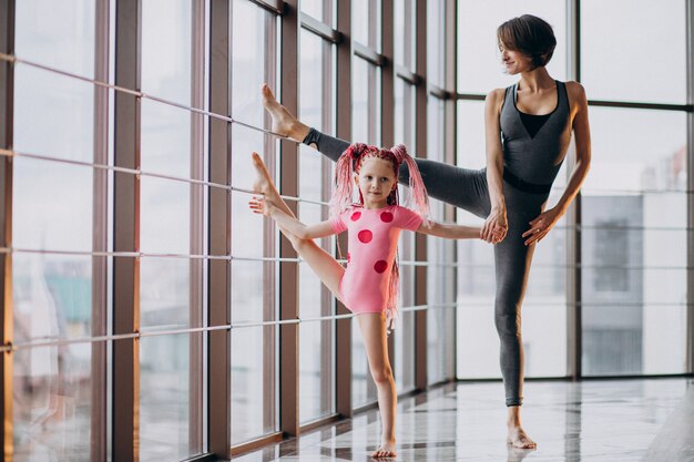 Madre con figlia piccola a praticare yoga vicino alla finestra