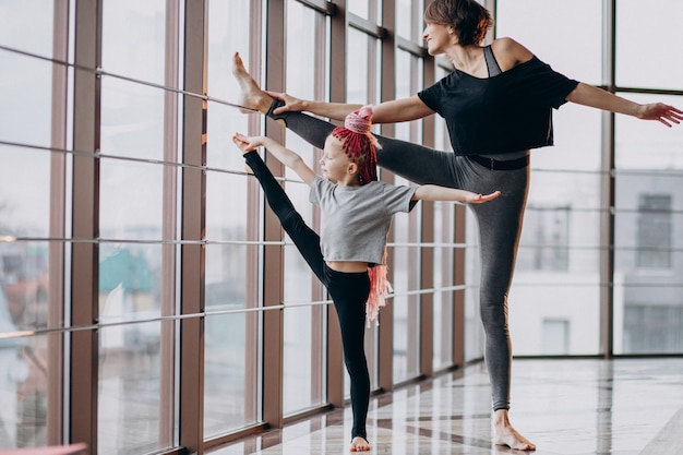 Madre con figlia piccola a praticare yoga vicino alla finestra