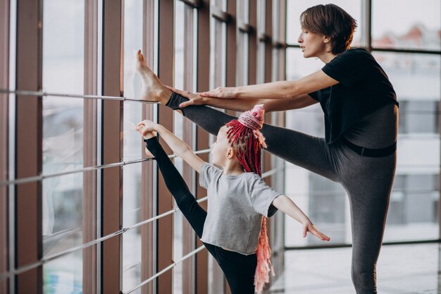 Madre con figlia piccola a praticare yoga vicino alla finestra