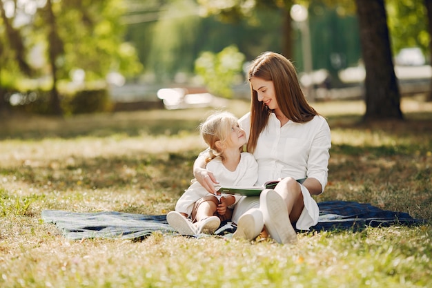 Madre con figlia piccola seduta su un plaid e leggere il libro