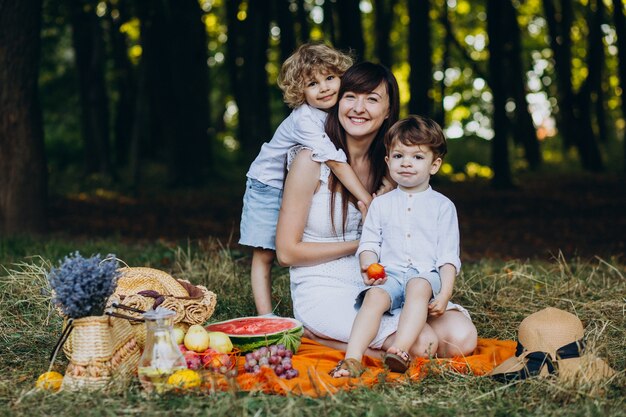 Madre con i suoi figli che hanno picnic nella foresta