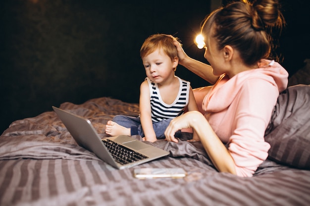 Madre con il figlio che lavora al computer a letto