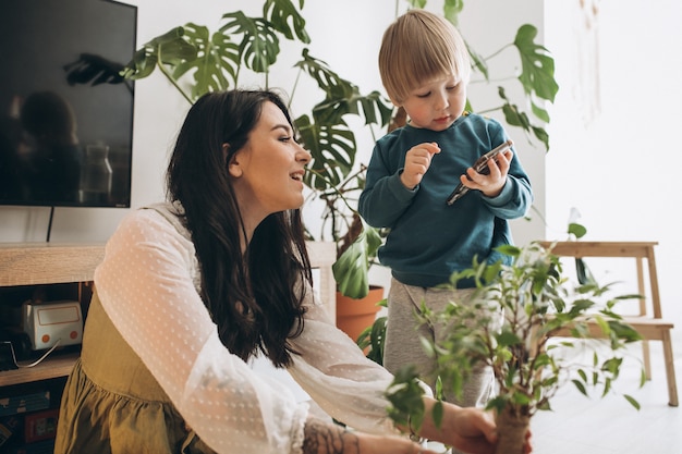 Madre con il piccolo figlio che coltiva le piante a casa